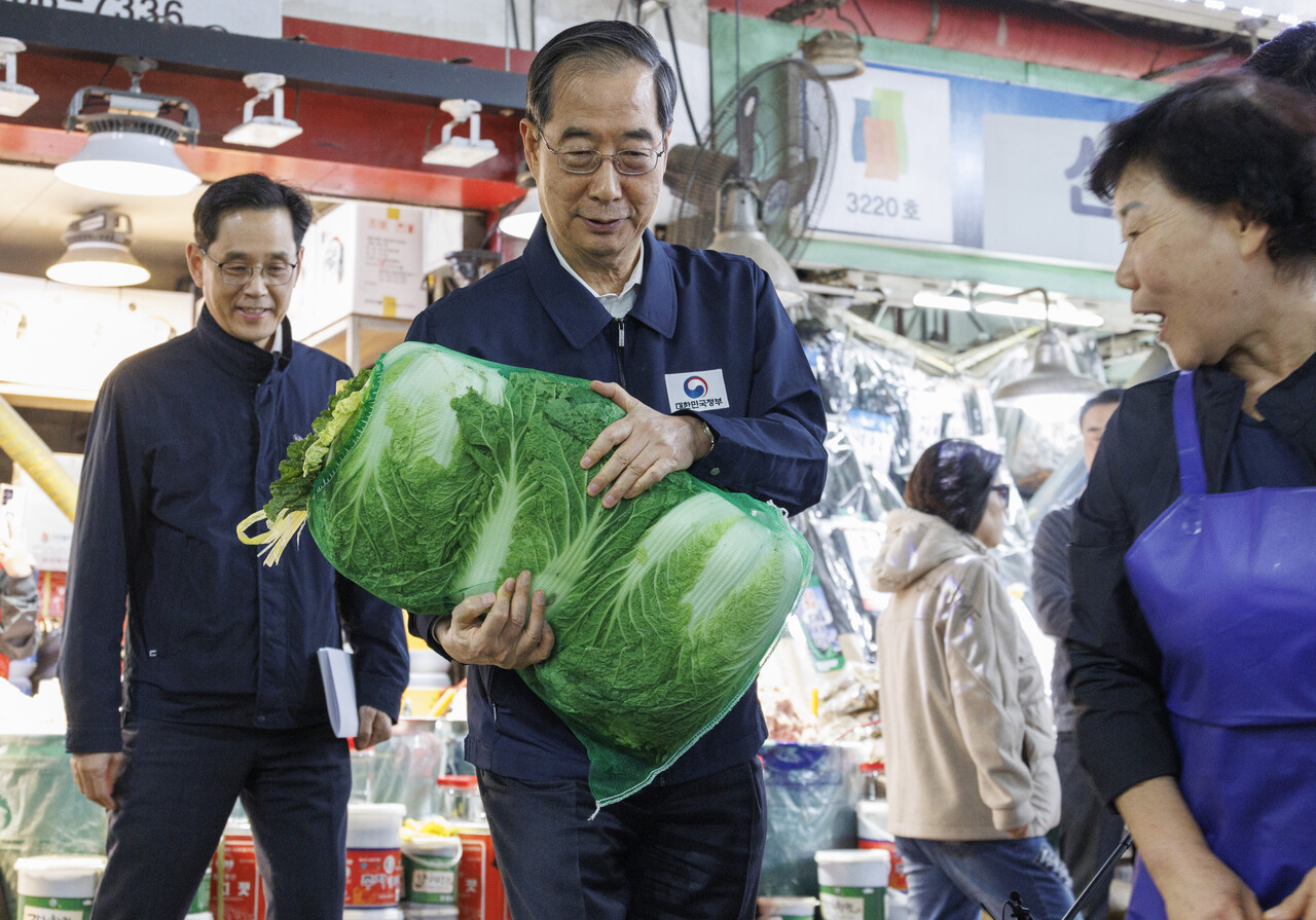 한덕수 국무총리가 지난 24일 오후 농수산물 물가 점검을 위해 서울 마포구 마포농수산물시장을 찾아 직접 배추를 골라 구입하고 있다.