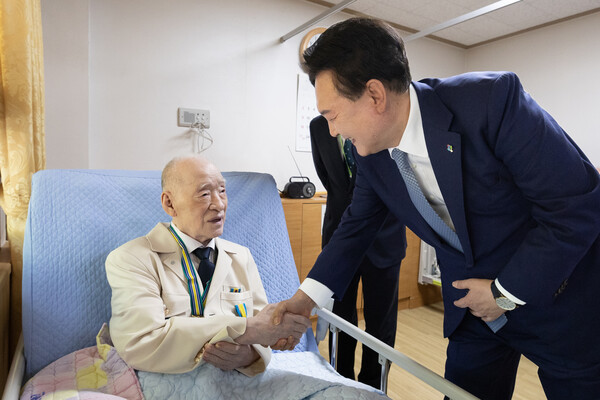윤석열 대통령이 21일 경기도 수원시 장안구 보훈요양원을 방문해 한 국가유공자에게 '영웅의 제복'을 선물하고 있다(연합뉴스)