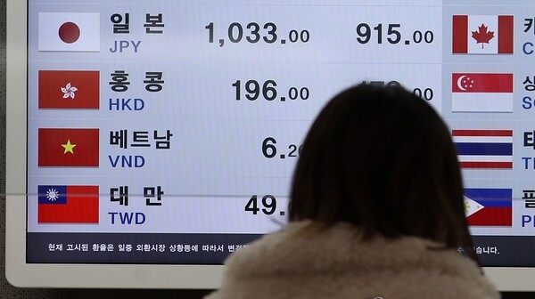 여성이 환율 게시판을 보고 있는 모습 여성이 환율 게시판을 보고 있는 모습