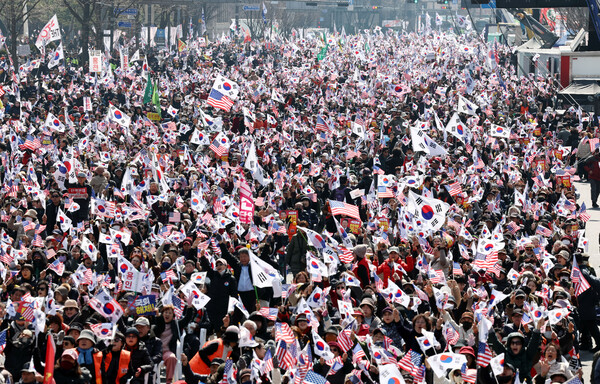  8일 서울 종로구 동화면세점 앞에서 열린 탄핵 반대 광화문 국민대회에서 참가자들이 태극기와 손팻말을 흔들고 있다(연합뉴스)