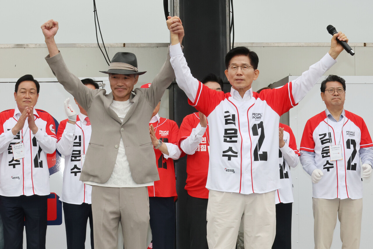 국민의힘 김문수 대선 후보가 지난 16일 경기 수원시 지동시장에서 열린 유세에서 서해상에서 북한군에 의해 피살된 공무원의 유족인 이래진 씨와 함께 손을 들어 보이며 시민들에게 인사하고 있다.