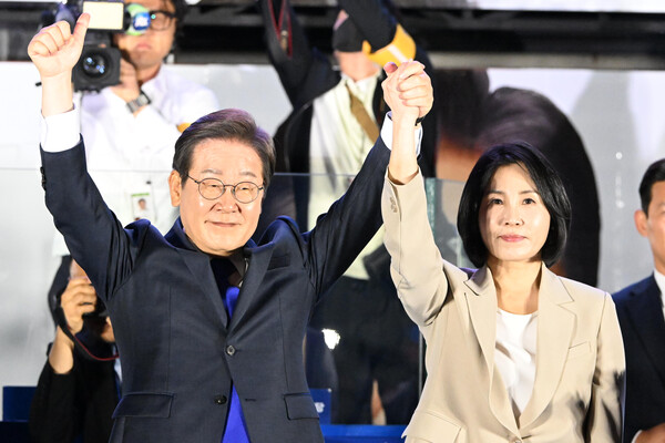 제21대 대통령 당선이 확실시되는 더불어민주당 이재명 대선 후보와 부인 김혜경 여사가 4일 서울 여의도 국회 인근에서 당 주최로 열린 국민개표방송 행사에 참석해 시민들을 향해 두 팔을 들어올려 인사하고 있다(연합뉴스)