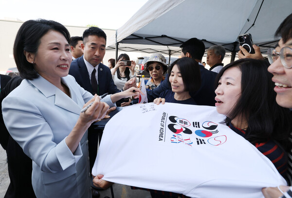 G7 정상회의에 참석하는 이재명 대통령과 함께 캐나다를 방문한 김혜경 여사가 17일(현지시간) 캘거리 한인회관에서 환영나온 주민들의 요청에 티셔츠에 서명하고 있다(연합뉴스)