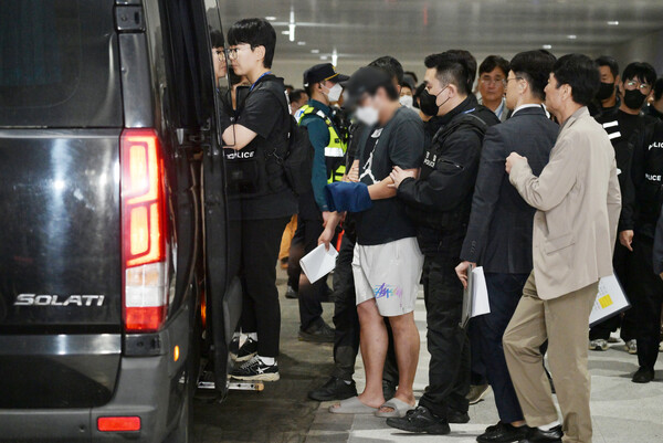 캄보디아 온라인 사기에 가담해 구금된 한국인들이 지난 18일 오전 인천국제공항 제2터미널을 통해 송환돼 호송차에 오르고 있다. 이날 송환에는 경찰 호송조 190여명이 투입됐다 [사진=연합뉴스]